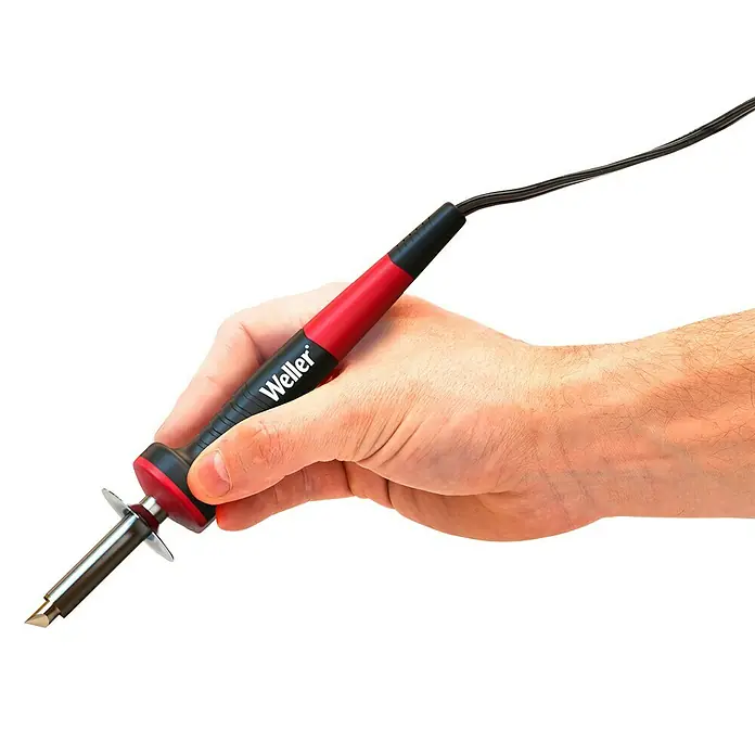 Weller Brandmal-Set WLIWBK2523C - Gesamtumfang: 15 -tlg. - Nahaufnahme einer Hand, die einen Weller-Lötkolben mit rotem und schwarzem Griff vor einem schwarzen Hintergrund hält.