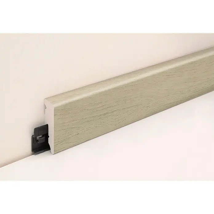 Profiles and more Sockelleiste KU51L Versailles - 240 cm x 15 mm x 50 mm - Nahaufnahme einer montierten, hellbraunen Sockelleiste mit Holzstruktur an einer Wand, befestigt mit einem schwarzen Clip-System.