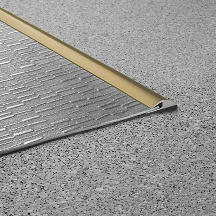 LOGOCLIC Einfassleiste - Beige/Braun, 1 m x 26 mm x 3 mm, Montageart: Kleben - Detailaufnahme eines Bodenprofils mit Goldakzent, das einen Übergang zwischen zwei verschiedenen Bodenbelägen schafft.
