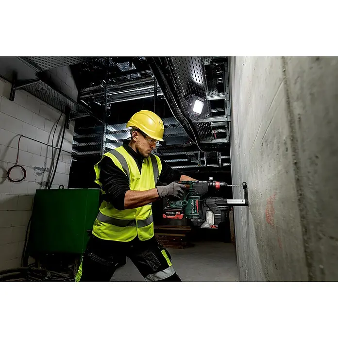 Metabo CAS 18V LED-Akkustrahler BSA 18 LED 4000 - 18 V, Ohne Akku - Ein Bauarbeiter mit Schutzhelm bohrt mit einem Metabo Bohrhammer ein Loch in eine Betonwand. Der Bohrhammer ist das zentrale Produkt.