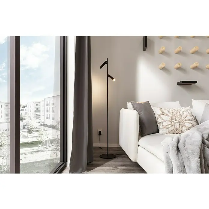 Regalux Wandboard XL4 - L x B x H: 23,5 x 118 x 3,8 cm, Schwarz, Belastbarkeit: 12 kg - Eine moderne Stehlampe mit zwei verstellbaren Leuchten steht neben einem weißen Sofa in einem hellen Raum. Stilvolles Design für gemütliche Beleuchtung.