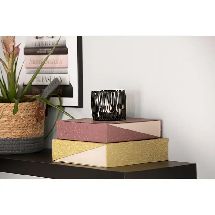 Regalux Wandboard XL4 - L x B x H: 23,5 x 118 x 3,8 cm, Schwarz, Belastbarkeit: 12 kg - Dekorative Aufbewahrungsboxen, gestapelt auf einem Regal mit einer eleganten Kerzenhalter-Dekoration.