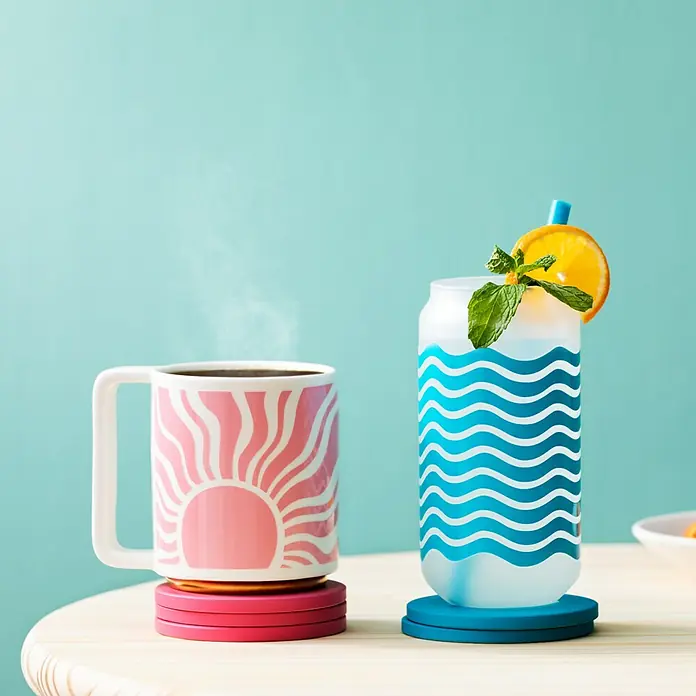 Cricut Joy Transferfolie Transfer Tape Linerless - L x B: 304 x 14 cm - Heißes Getränk im Sunrise-Becher und erfrischender Cocktail im Wellenglas, beide stehen auf farbenfrohen Untersetzern.