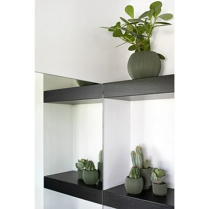 Capi Europe Übertopf rund Nature Groove - Außenmaß (Ø x H): 21,5 x 21,5 cm, Grün, Polyester - Pflanzenarrangements in stilvollen, geriffelten Töpfen auf dunklen Regalen, reflektiert in einem Spiegel, der die grüne Dekoration hervorhebt.
