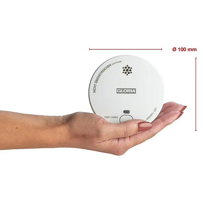 Gloria Rauchwarnmelder R-1 - Durchmesser: 100 mm, Batterielaufzeit: 2 Jahre, Alarmsignal: 85 dB - Eine Hand hält einen weißen Gloria Rauchmelder. Durchmesser des Rauchmelders beträgt 100 mm.\n