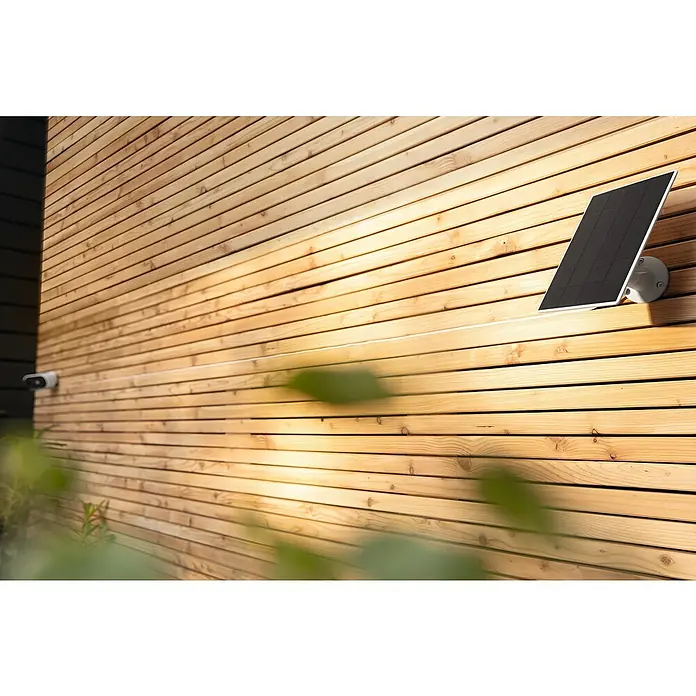 Abus Solarmodul PPIC91600 W PRO - L x B x H: 12 x 1 x 17 cm, IP65 - Nahaufnahme einer Solarpanel-Kamera, die an einer Holzwand montiert ist und für nachhaltige Überwachung im Außenbereich sorgt.