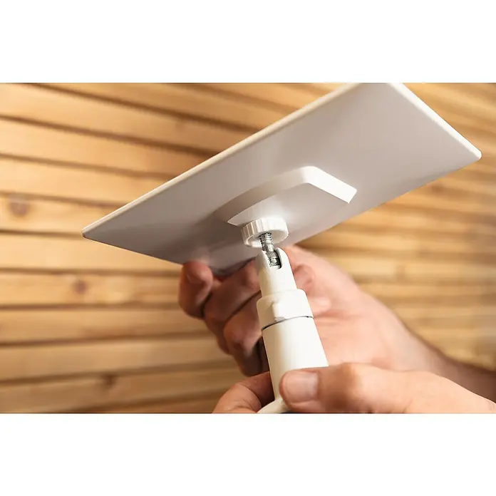 Abus Solarmodul PPIC91600 W PRO - L x B x H: 12 x 1 x 17 cm, IP65 - Nahaufnahme einer Hand, die eine Halterung für eine weiße rechteckige Oberfläche vor einer Holzwand befestigt.