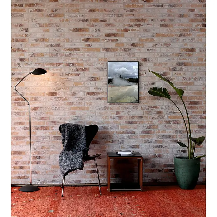 Celina Klinker Verblendstein Vintage Paris - 5,2 x 24 cm, Gelb/Weiß, Steinoptik - Innenaufnahme eines Zimmers mit Backsteinmauer, Lampe, Sessel mit Decke, Bild, Tisch mit Büchern, Zimmerpflanze und rotem Teppich.