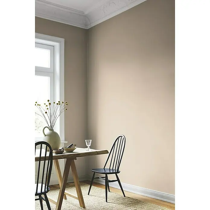 Alpina Wandfarbe Feine Farben - Wiege des Aromas, Matt, 2,5 l, Konservierungsmittelfrei - Detailaufnahme eines minimalistischen Essbereichs mit einem Holztisch und schwarzen Stühlen vor einer neutralen Wand.
