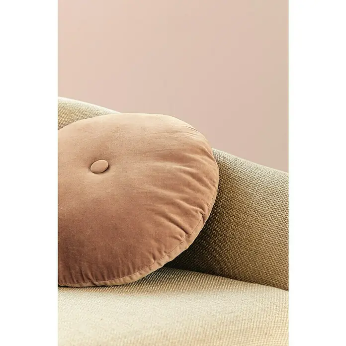 Alpina Wandfarbe Feine Farben - Palast der Ewigkeit, Matt, 2,5 l, Konservierungsmittelfrei - Nahaufnahme eines runden, pfirsichfarbenen Samtkissens mit Knopf auf einem strukturierten Sofa, das eine elegante Note verleiht.