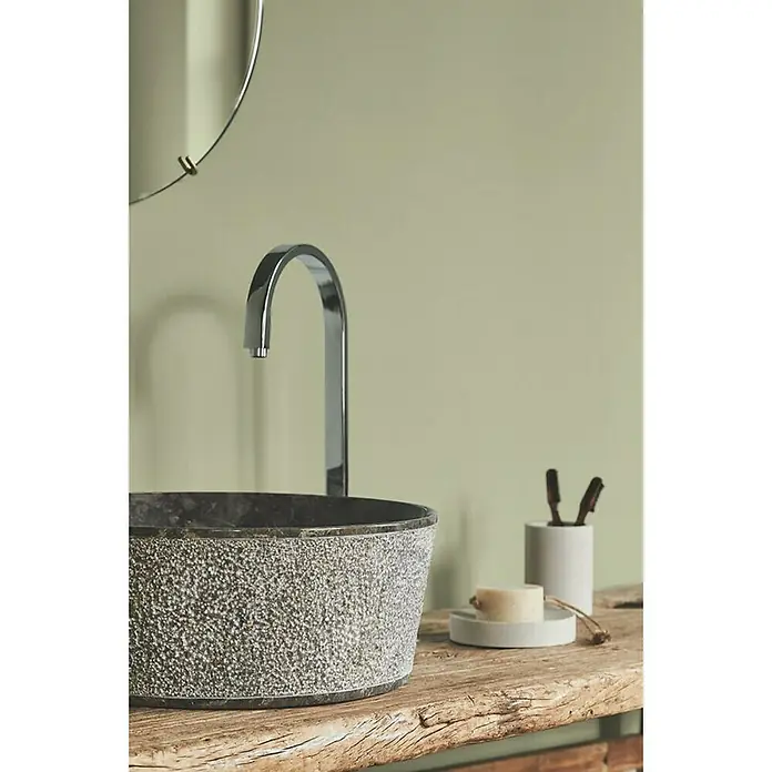 Alpina Wandfarbe Feine FarbenEssenz der Natur, Matt, 2,5 l, Konservierungsmittelfrei - Nahaufnahme eines Waschbeckens aus Stein mit Armatur, Seife und Bürsten auf einem rustikalen Holztisch. Elegantes Badezimmerdesign mit natürlichen Elementen.