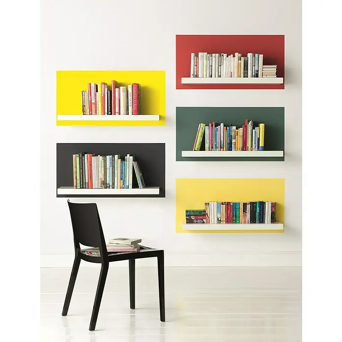 Alpina Vollton- & Abtönfarbe Color - Sunny Yellow, Matt, 250 ml, Lösemittelfrei - Bücherregale in verschiedenen Farben an einer weißen Wand, darunter ein schwarzer Stuhl mit Büchern.