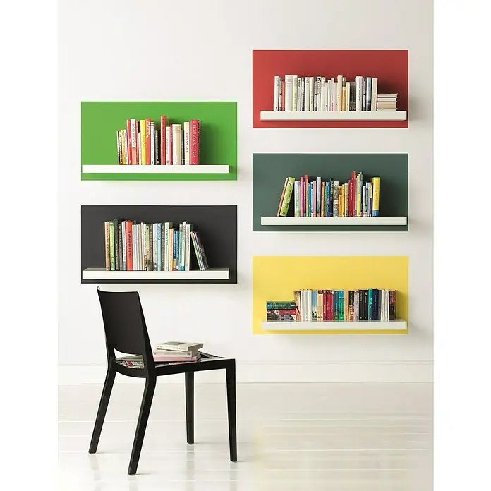Alpina Vollton- & Abtönfarbe Color - Grass Green, Matt, 250 ml, Lösemittelfrei - Wandregale mit bunten Hintergründen und Büchern an einer weißen Wand, darunter ein schwarzer Stuhl.