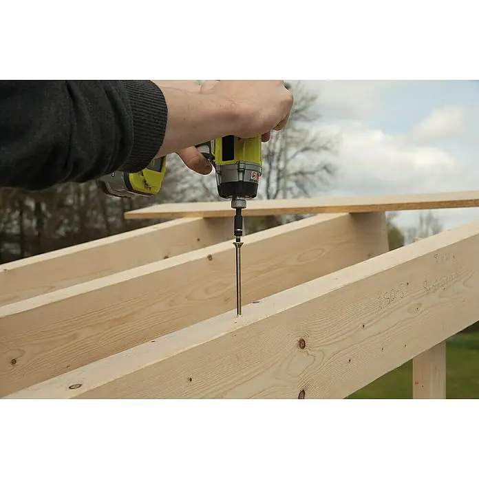 Wolfcraft Bit-Box Torx - 7 -tlg. - Nahaufnahme eines gelben Ryobi-Akkuschraubers, der eine lange Schraube in eine Holzkonstruktion dreht.