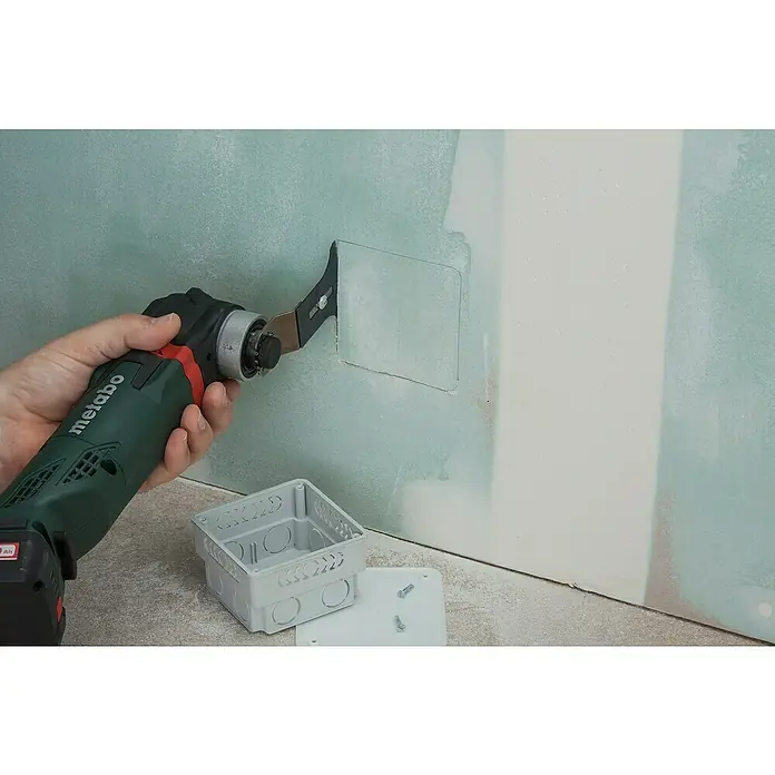 Wolfcraft Tauchsägeblatt Pro mit Tiefenanschlag - 65 mm, 1 Stk. - Das Bild zeigt eine Metabo Multifunktionswerkzeug beim Schneiden eines Lochs in eine Trockenbauwand, um eine Steckdose zu installieren.