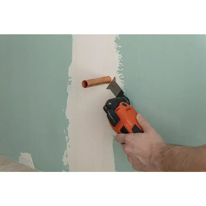Wolfcraft Tauchsägeblatt Expert BiM - Arbeitsbreite: 50 mm - Oszillierendes Werkzeug Starlock Plus in Aktion, präzise für Trockenbauarbeiten an einer Wand mit Kupferrohr.
