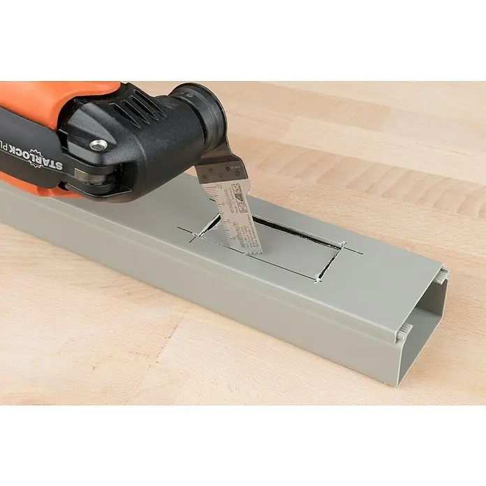 Wolfcraft Tauchsägeblatt Expert BiM - Arbeitsbreite: 20 mm - Eine oszillierende Multifunktionswerkzeug schneidet ein Rechteck aus einem grauen Kabelkanal auf einer hellen Holzoberfläche.