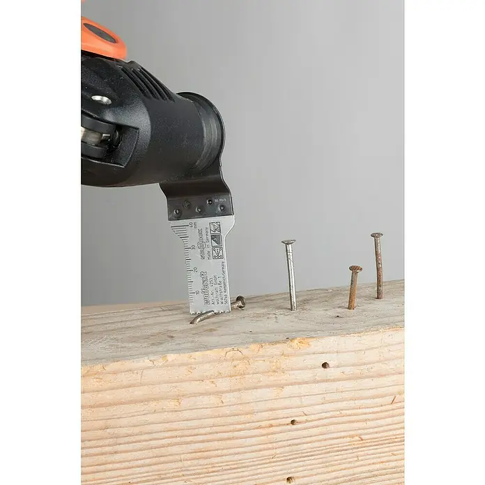 Wolfcraft Tauchsägeblatt Expert BiM - Arbeitsbreite: 20 mm - Das Bild zeigt ein Wolfcraft-Sägeblatt, das an einem Multitool befestigt ist und zum Schneiden von Nägeln in einem Holzbrett verwendet wird.