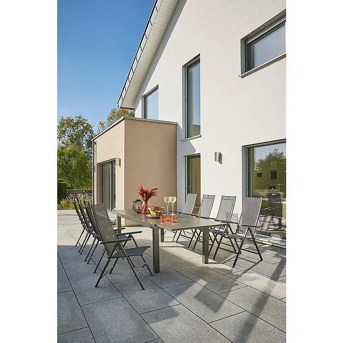 Sunfun Maja Slim Gartenmöbel-Set Stone - 9 -tlg., Sintered Stone, Aluminium, Textilen, Anthrazit - Elegante graue Gartentischgarnitur mit Stühlen auf einer Terrasse vor einem modernen Haus. Ideal für stilvolle Outdoor-Momente.