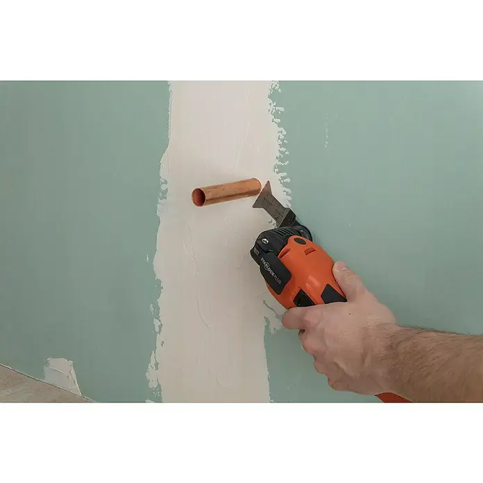 Wolfcraft Tauchsägeblatt Expert BiM - Arbeitsbreite: 44 mm - Ein orangefarbenes oszillierendes Multifunktionswerkzeug beim Schneiden um ein Kupferrohr in einer Wand.