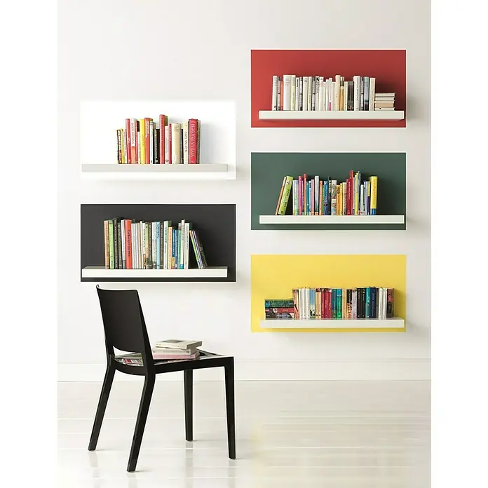 Alpina Vollton- & Abtönfarbe Color - Snow White, Matt, 250 ml, Lösemittelfrei - Verschiedenfarbige Bücherregale mit Büchern an einer weißen Wand, darunter ein schwarzer Stuhl mit Büchern.