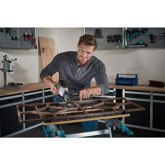 Wolfcraft Topfbürste - Stahldraht, 80 mm, Art Draht: Gewellt - Mann schleift Metall mit einer Schleifmaschine an einer Werkbank in einer Werkstatt. Schutzbrille wird getragen.