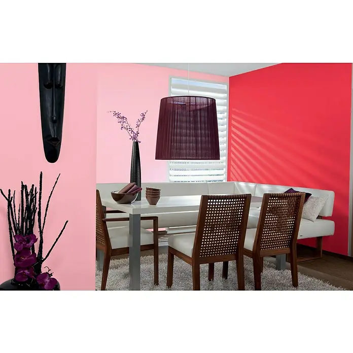 Alpina Vollton- & Abtönfarbe Color - Fire Red, Matt, 250 ml, Lösemittelfrei - Esszimmer mit weißem Tisch, Stühlen und dekorativen Elementen wie einer Maske und einer Lampe. Die Wände sind in Pink- und Rottönen gehalten.