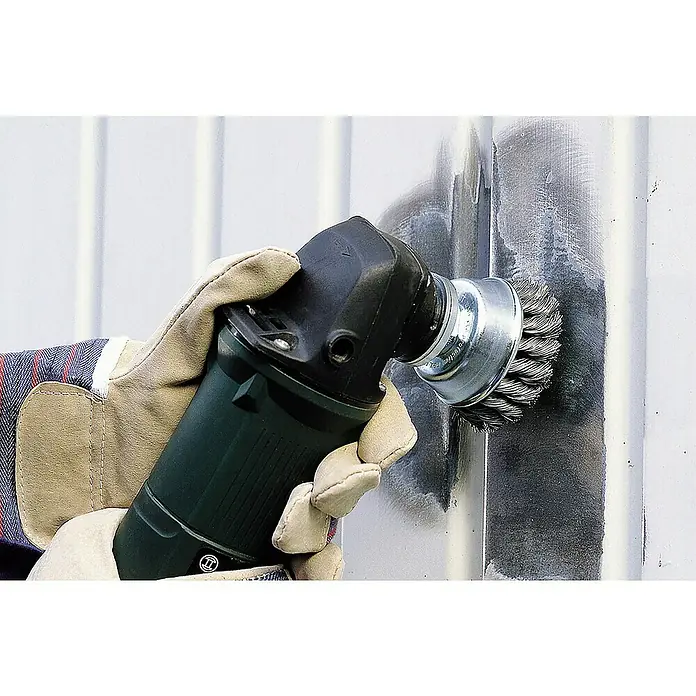 Wolfcraft Topfbürste - Durchmesser: 90 mm, Stahldraht - Eine Hand mit Handschuh benutzt eine Drahtbürsten-Schleifmaschine, um eine Metalloberfläche zu reinigen.