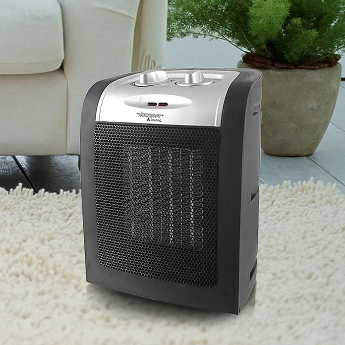 Voltomat HEATING Heizlüfter - 900 kW - 1.800 W, Schwarz, 12 x 17 x 22 cm - Abbildung eines tragbaren Heizgeräts. Die Heizung hat eine schwarze Gitterfront und einen silbernen Drehknopf oben für die Temperaturregelung.