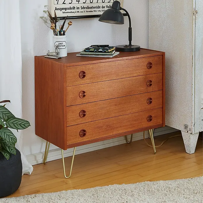 Wagner System Möbelfuß Hairpinlegs - Stahl, Höhe: 20 cm, Gold - Eine Kommode aus Holz mit vier Schubladen und goldenen Beinen, dekoriert mit einer Lampe und einer Vase.
