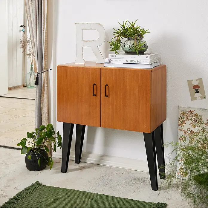Wagner System Möbelfuß - Höhe: 10 cm, Stahl, Schwarz - Das Bild zeigt einen Holzschrank mit schwarzen Beinen, dekoriert mit Pflanzen, Büchern und einem Buchstaben, der eine gemütliche Atmosphäre schafft.