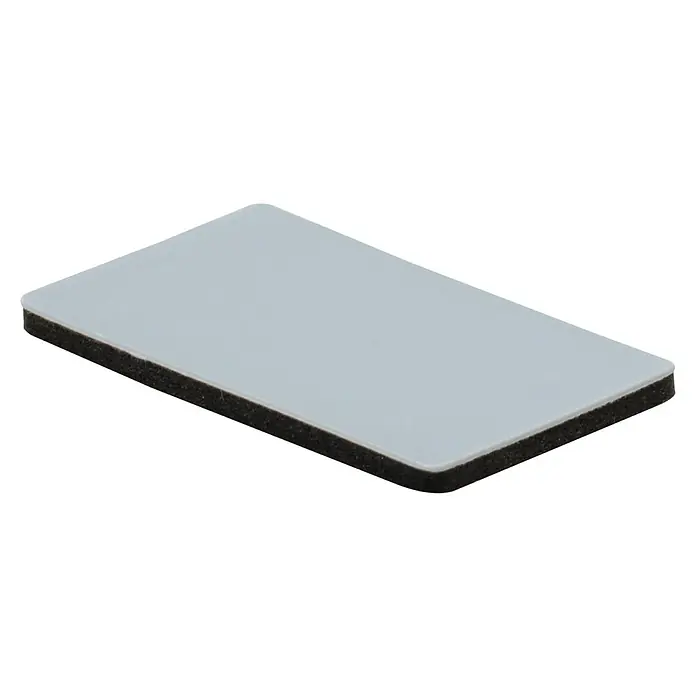 Wagner System Möbelgleiter - 16 x 26 mm, Kleben, 16 Stk. - Bild eines rechteckigen Objekts mit einer grauen Oberfläche und einer schwarzen Schaumstoffunterlage, das eine rutschfeste Funktion bietet.