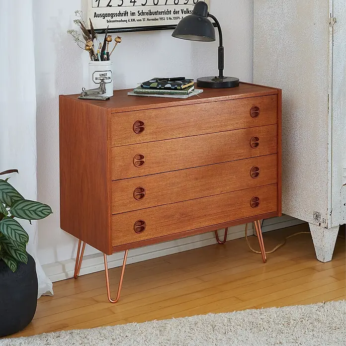 Wagner System Möbelfuß Hairpinlegs - Stahl, Höhe: 10 cm, Rosé Gold - Ein Holzschrank mit vier Schubladen und modernen Kupferbeinen, der eine stilvolle und funktionale Aufbewahrungslösung bietet.
