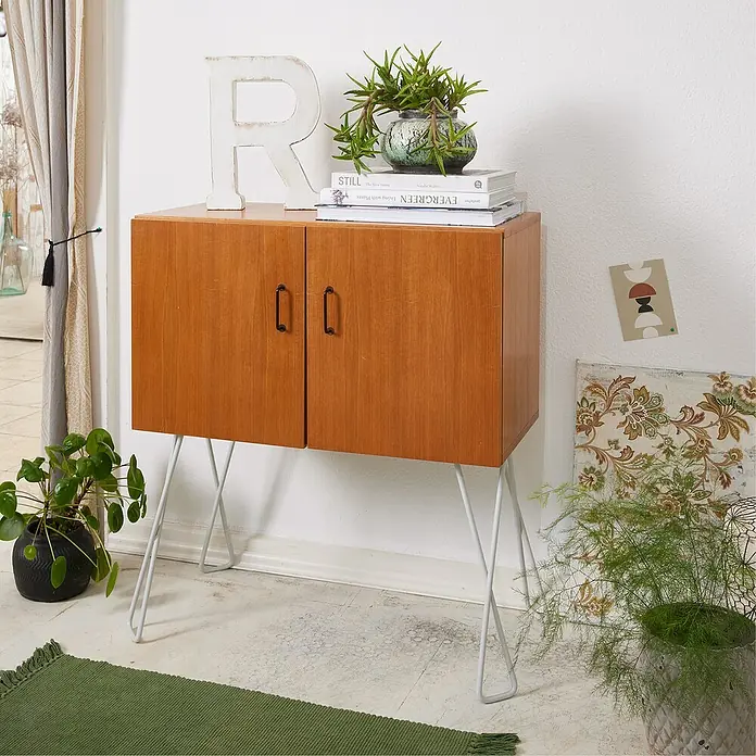 Wagner System Möbelfuß Hairpin Twist - Höhe: 400 mm, Stahl, Hellgrau - Ein stilvolles Sideboard mit Holztüren und schlanken, weißen Metallbeinen, dekoriert mit Pflanzen und einem dekorativen Buchstaben R.