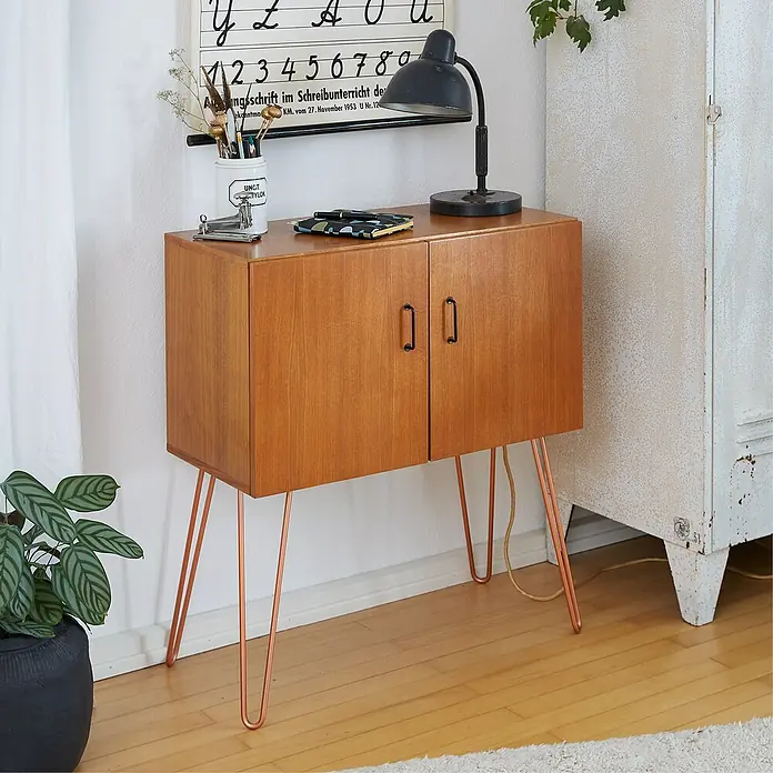 Wagner System Möbelfuß Hairpinlegs - Stahl, Höhe: 40 cm, Rosé Gold - Schrank aus hellem Holz mit Kupferbeinen und zwei Türen mit Griffen. Auf der Oberseite stehen Lampe, Stifte und Büroklammern.