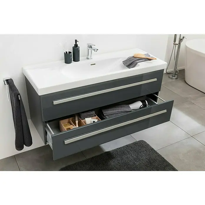 Lanzet K1 Badmöbel-Set K11G1 - 119,2 cm, Grafit - Ein moderner grauer Badezimmerschrank mit weißem Waschbecken, teilweise geöffneter Schublade mit Badartikeln und Handtüchern.