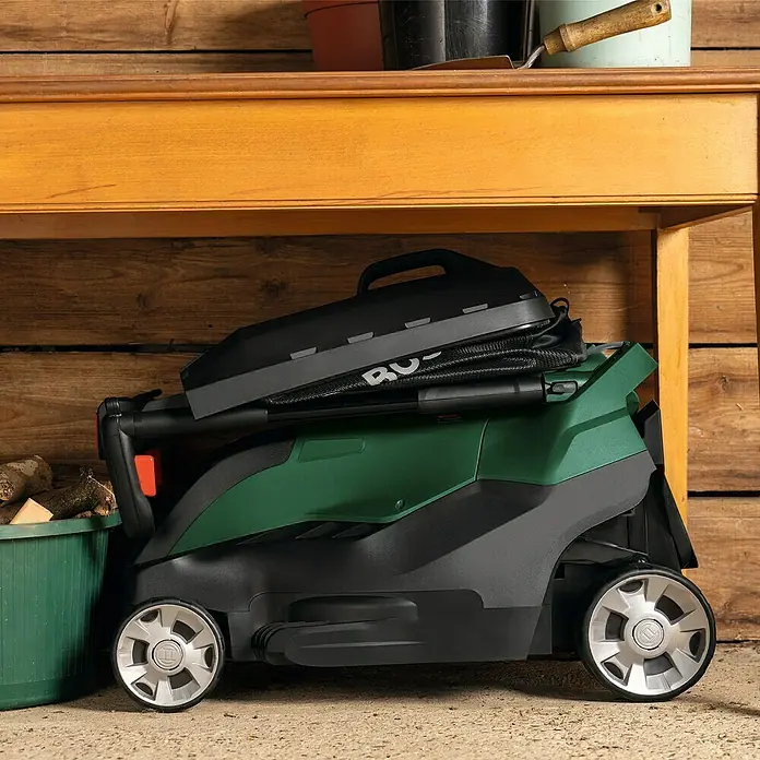 Bosch Elektro-Rasenmäher AdvancedRotak 40-650 - 1.700 W, Schnittbreite: 40 cm - Ein grüner Bosch Rasenmäher steht unter einem Tisch, bereit für den Einsatz im Garten. Praktische Gartentechnik für den perfekten Rasen.