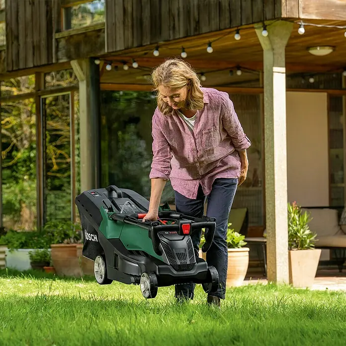 Bosch Elektro-Rasenmäher AdvancedRotak 40-650 - 1.700 W, Schnittbreite: 40 cm - Frau bereitet einen Bosch-Rasenmäher für die Gartenarbeit vor, der Rasenmäher ist kompakt und leicht zu verstauen.