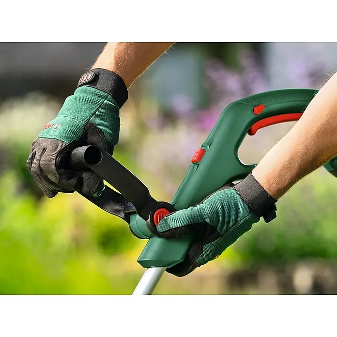 Bosch Power for All 18V Akku-Rasentrimmer UniversalGrassCut 18V-23-450 - 18 V, Ohne Akku - Nahaufnahme von Händen in Arbeitshandschuhen, die einen Rasentrimmer halten.