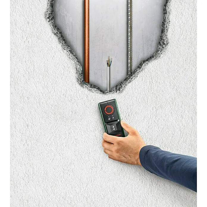 Bosch Detector Truvo II - Apto para: Detectar cables eléctricos y metal, Profundidad de detección: Máx. 70 mm de metales ferrosos - Un operador utiliza un detector Bosch en una pared con tubos expuestos para detectar elementos ocultos.