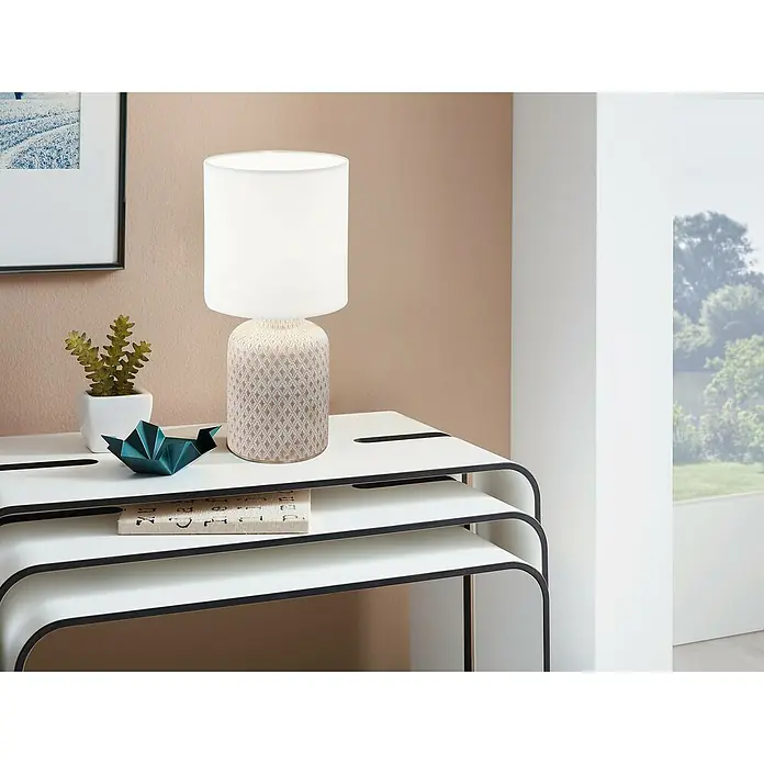 Eglo Lámpara de sobremesa redonda Bellariva - 40 W, Ø x Al: 15 x 32 cm, Blanco/Crema, E27 - Una moderna lámpara de noche con pantalla blanca y base estampada sobre una mesa auxiliar blanca con borde negro.