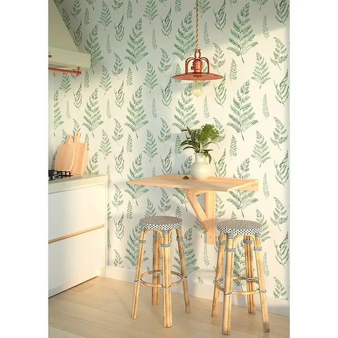 Astigarraga Klapptisch - 53,6 mm x 79,5 mm x 59 cm, Kiefer - Diese Küchenaufnahme zeigt einen Holztisch mit zwei Hockern vor einer Wand mit Pflanzenmuster. Die Lampe erhellt die Szene warm.