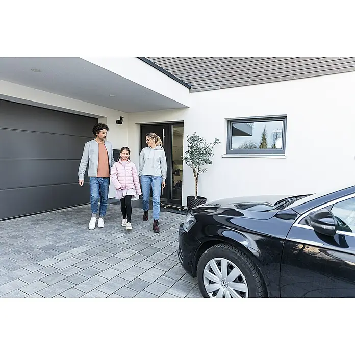 Abus Überwachungskamera PPIC46520 BK - IP66 - Familie vor einem modernen Haus mit grauer Garage und schwarzem Auto.