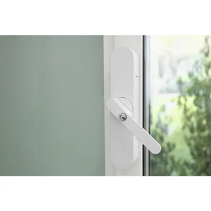 Abus Funk-Türschlossantrieb Wintecto one FCA4100 W - Geeignet für: Fenster, Weiß, Bedienung: Über App - Nahaufnahme eines weißen Fenstergriffs mit Schloss, montiert an einem modernen Fensterrahmen. Blick nach draußen ins Grüne.