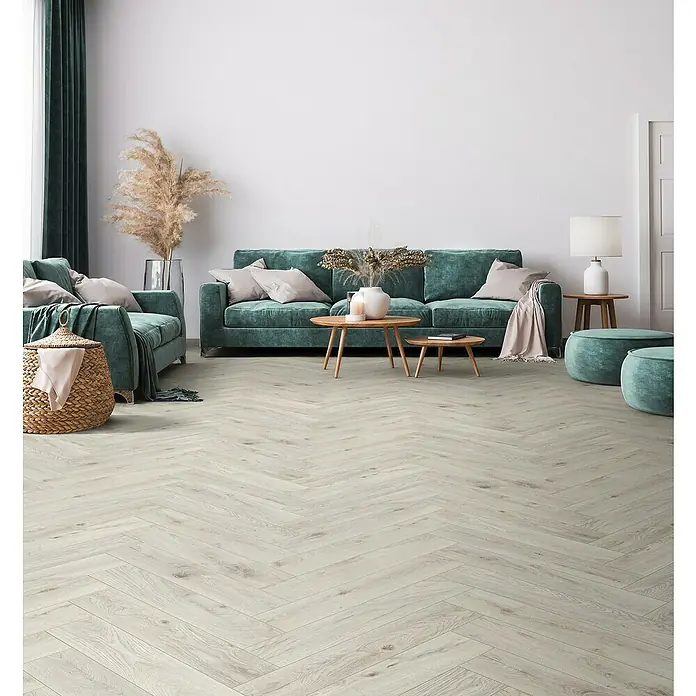 Krono Original Laminat Herringbone - Chantilly Oak, Fischgrät, 630 x 126 x 8 mm - Helles Fischgrätparkett verlegt in einem eleganten Wohnzimmer mit grünen Möbeln, das eine moderne und stilvolle Atmosphäre schafft.