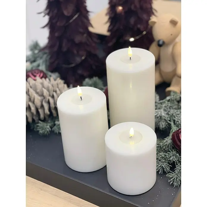 DeluxeHomeart LED-Kerze Indoor - Weiß, Ø x H: 7,5 x 15 cm, Echtwachs - Drei weiße Stumpenkerzen mit LED-Flamme auf einem dekorierten Tablett. Weihnachtliche Atmosphäre mit Tannenzweigen und Deko.