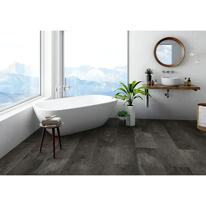 Classen Laminat Visiogrande - Nero slate, 604 x 280 x 8 mm - Ein Badezimmer mit dunklen Bodenfliesen, einer freistehenden Badewanne und einem Waschtisch mit rundem Spiegel.
