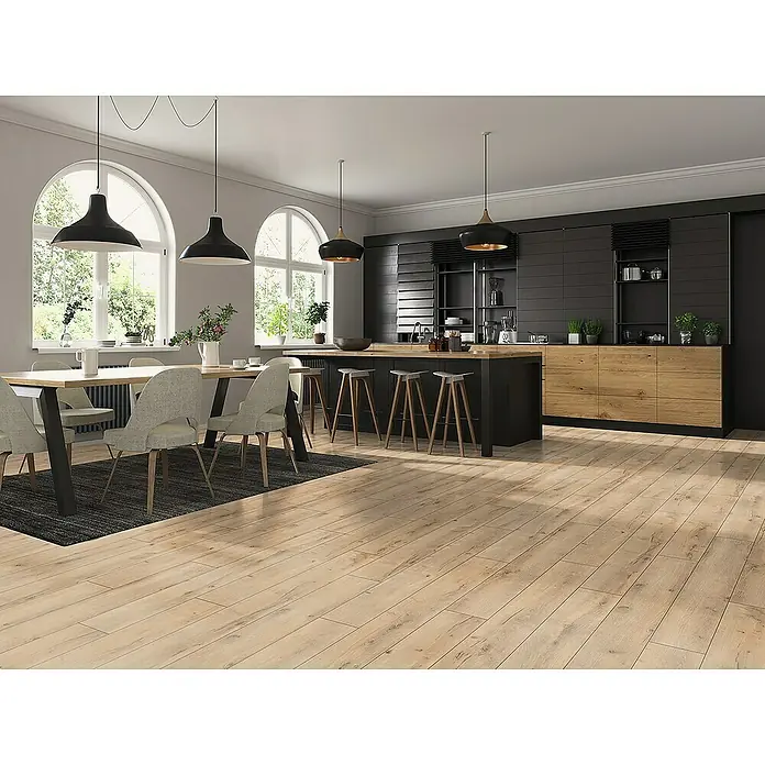 Classen Laminat 831-4 - Oak Rustic beige, Landhausdiele, 1.286 x 194 x 8 mm - Helle Holzböden ergänzen eine moderne Küche mit einer Kochinsel, schwarzen Schränken und Lampen, die über dem Esstisch hängen.