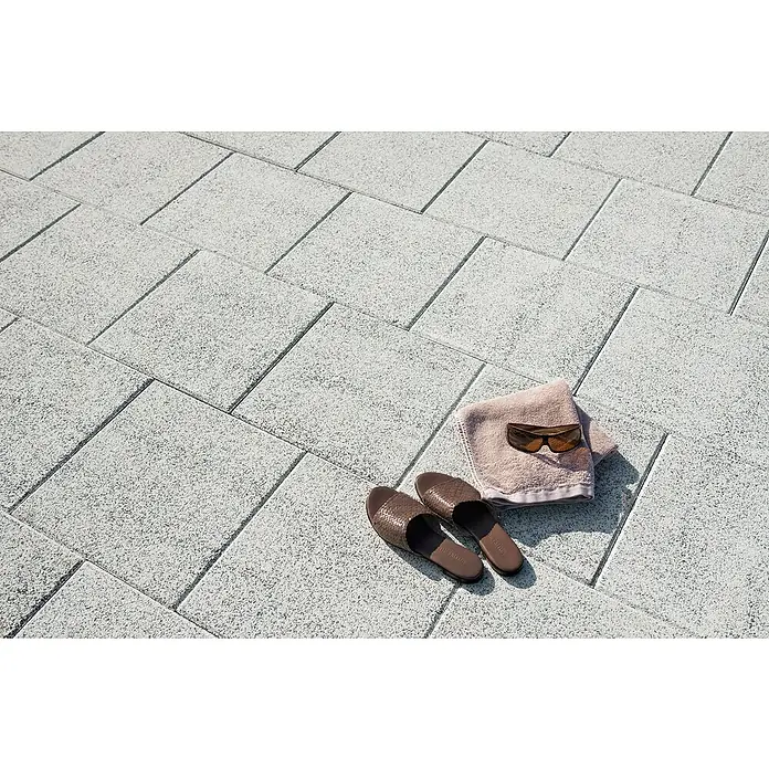 Diephaus Terrassenplatte Phoenix40 x 40 x 4 cm, Weiß, Beton - Sandalen, Handtuch und Sonnenbrille auf hellgrauem Pflaster.