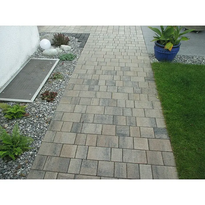 Diephaus Pflasterstein Vacaville - Muschelkalk, 45 Stk., Rechteckig - Ein gepflasterter Weg führt durch einen Garten mit einer blauen Topfpflanze. Die Pflastersteine bilden ein attraktives Muster.